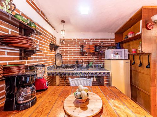 a kitchen with a wooden table and a brick wall at Cabañas Elsa María, Cabañas para Hospedaje con Alberca y Jardín de Eventos in Atlautla
