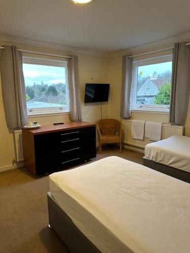 a bedroom with two beds and a desk and two windows at The Kinross Salutation Hotel in Kinross