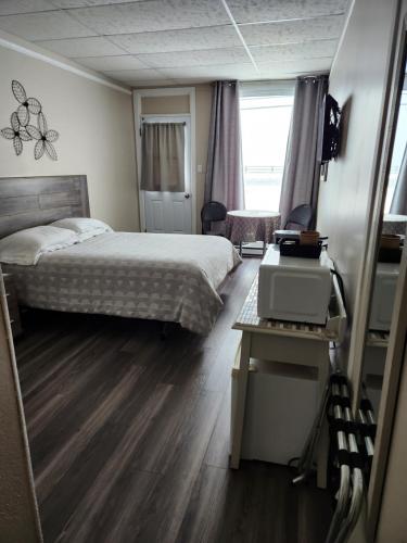 a bedroom with a bed and a desk with a computer at Motel Nanook in Cap-Chat