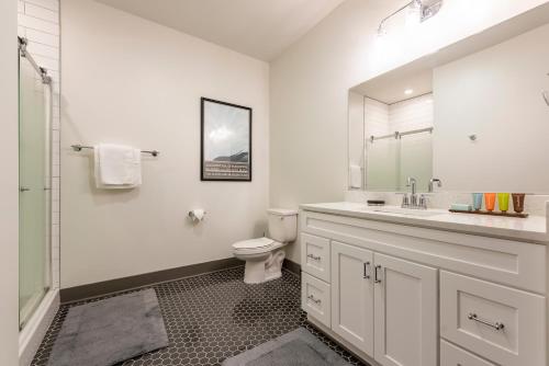 Baño blanco con aseo y lavamanos en ABODES ApartHotel, en Rochester