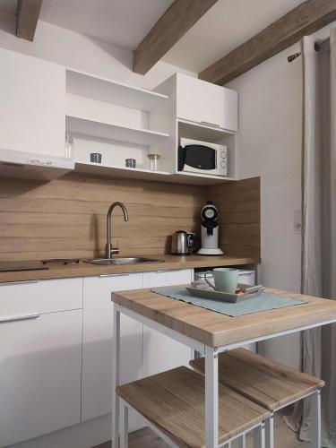 - une cuisine avec des placards blancs et une table avec un évier dans l'établissement Studio Cosy dans la maison d'enfance de Jean Giono, à Manosque
