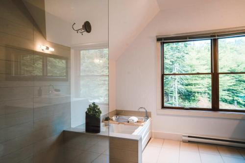 a bathroom with a sink and a shower and a window at Captivating view of Lake Superieur in Lac-Superieur