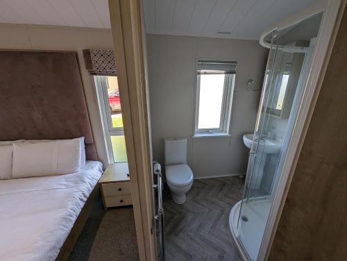 a bedroom with a bed and a shower and a toilet at Morrelo View 24, Cherry Tree Holiday park. in Great Yarmouth