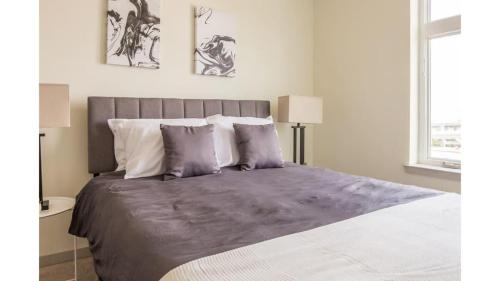 Stunning Nulu 1BR CozySuites 04 في لويزفيل: غرفة نوم مع سرير كبير مع ملاءات ووسائد أرجوانية