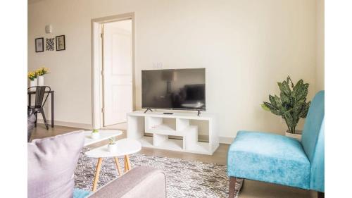 a living room with a tv and a blue chair at Stunning Nulu 1BR CozySuites 04 in Louisville