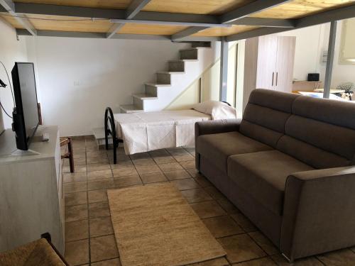 sala de estar con sofá y escalera en La casa di Desy&Giò, en Erice
