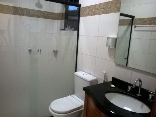 La salle de bains est pourvue de toilettes, d'un lavabo et d'un miroir. dans l'établissement Pousada Paraíso das Orquídeas, à Nova Santa Medianeira