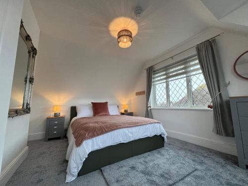 a bedroom with a large bed and a window at Ocean Cottage, Ferring - seaside cottage moments from the beach and Bluebird cafe in Ferring