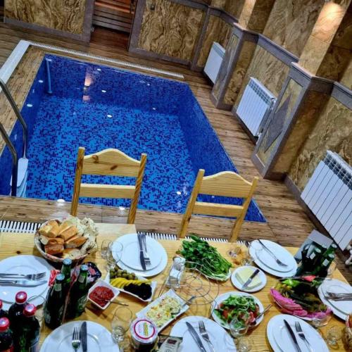 a table with plates of food and a swimming pool at Rubin Hotel in Goris
