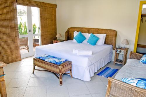 a bedroom with a large bed with blue pillows at Quinta Brasilis Boutique Hotel Paraty in Paraty