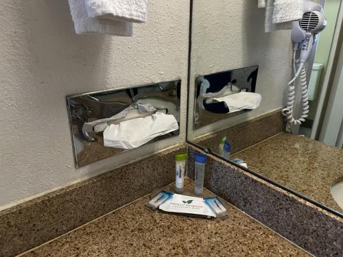 a bathroom with two mirrors and a sink with towels at Budget Inn Laramie in Laramie