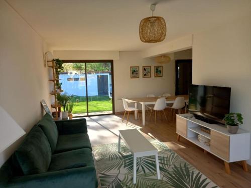 un salon avec un canapé vert et une télévision dans l'établissement Jolie maison 3 chb et jardin proche Arcachon, à La Teste-de-Buch