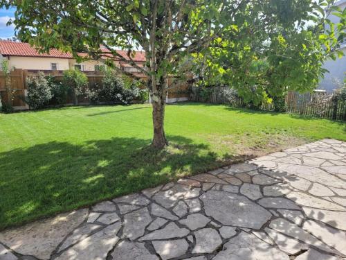 un arbre dans une cour avec une passerelle en pierre dans l'établissement Jolie maison 3 chb et jardin proche Arcachon, à La Teste-de-Buch