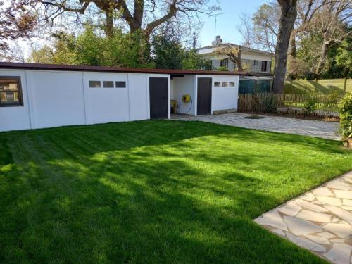 une grande cour avec un garage blanc dans l'établissement Jolie maison 3 chb et jardin proche Arcachon, à La Teste-de-Buch