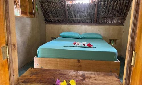 a bedroom with a bed with blue sheets and flowers on it at La Aldea Hostel, Camping y Hamacas in Palomino