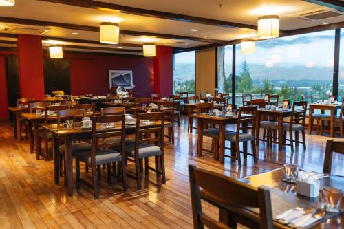 a restaurant with wooden tables and chairs and large windows at Loi Suites Chapelco Hotel in San Martín de los Andes