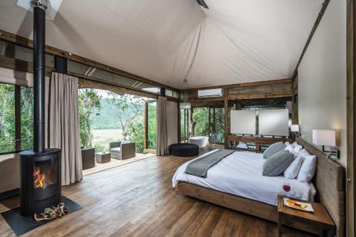 ein Schlafzimmer mit einem Bett und einem Kamin in der Unterkunft Kariega Game Reserve Settlers Drift in Alexandria