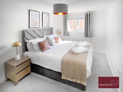 a bedroom with a large bed with white sheets and pillows at Jennett's Park, Bracknell - 2 Bedroom Home in Bracknell