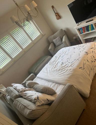 a bedroom with a bed with a chair and a window at Elmcroft Holiday Annex in Gillingham