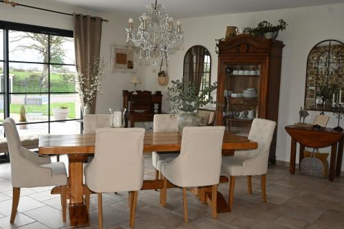 une salle à manger avec une table en bois et des chaises blanches dans l'établissement Aux 3 Forêts, à Bizeneuille