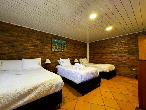 een slaapkamer met 2 bedden en een bakstenen muur bij Villa Carlinita in Sáchica