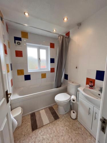 een badkamer met een bad, een toilet en een wastafel bij Cosy 2 bedroomed semi detached house in Brettell Lane