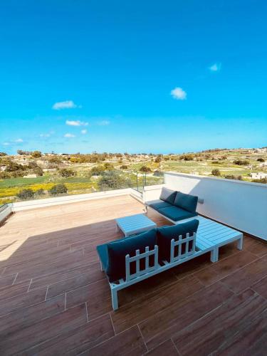 a patio with a couch and a table on a deck at Axtart Penthouse with Amazing Views in Marsaxlokk