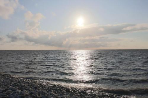 a sun shining over the water with a beach at Emily's Deichbude in einer historischen Villa in Dornumersiel in Dornum