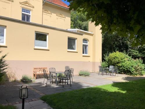 a patio with chairs and a table in front of a house at Emily's Deichbude in einer historischen Villa in Dornumersiel in Dornum