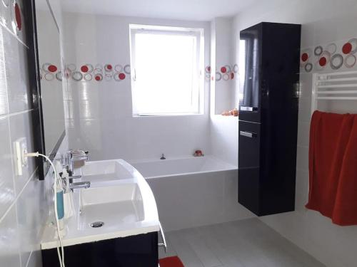La salle de bains est pourvue d'un lavabo, d'une baignoire et d'une fenêtre. dans l'établissement Maison agréable à deux pas d’une belle plage, à Lampaul-Plouarzel