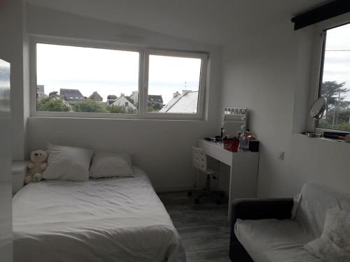 une chambre avec un lit et un bureau et deux fenêtres dans l'établissement Maison agréable à deux pas d’une belle plage, à Lampaul-Plouarzel