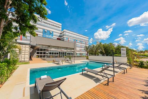 a swimming pool with chairs and a building at Rio hotel by Bourbon Indaiatuba Viracopos in Indaiatuba