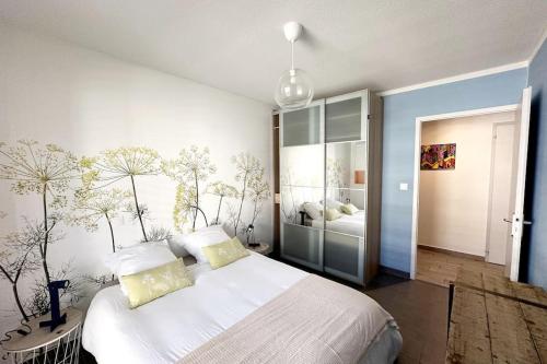 - une chambre avec un grand lit blanc et des oreillers jaunes dans l'établissement Bel Appart Design 2ch, Mairie, Pkg, Wifi, Terrasse, Port Marianne, à Montpellier