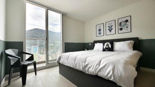 Apartaestudios con vista en el centro de Bogotá في بوغوتا: غرفة نوم بسرير وكرسي ونافذة