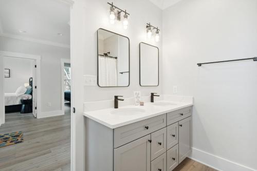 a white bathroom with a sink and two mirrors at Champagne and Sunsets in Edisto Island