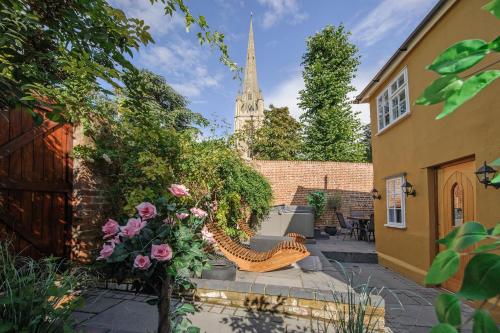 a garden with a bench and flowers and a church at Executive Suite with Private Hot Tub SkyTV in Saffron Walden