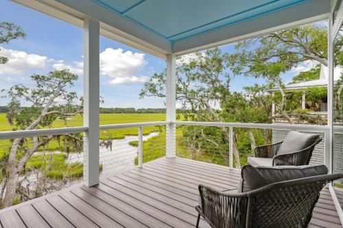 a porch with two chairs and a view of a field at Champagne and Sunsets in Edisto Island