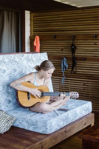 a woman sitting on a couch playing a guitar at Roam Yoga & Wellness Lodge in Bocas del Toro