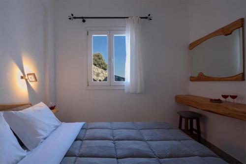 Κalamitsi Rooms & Apartments في كيمولوس: غرفة نوم بسرير ونافذة