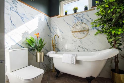 Impeccable 1-Bed Apartment in London في لندن: حمام مع حوض استحمام أبيض ومرحاض