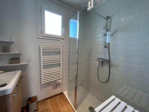 ein weißes Bad mit einer Dusche und einem Waschbecken in der Unterkunft La Guy’toune in Varaville