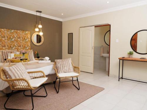 a bedroom with a bed and chairs and a bathroom at Lions View Accommodation in Nelspruit