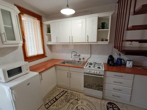 a kitchen with white cabinets and a sink and a stove at SZEKI Apartman in Gyula