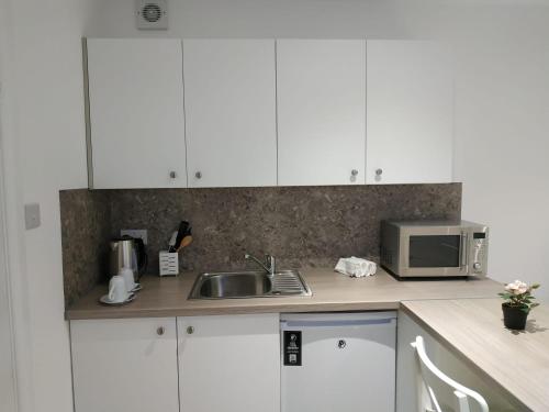 a kitchen with white cabinets and a sink and a microwave at Oceanik in Dublin