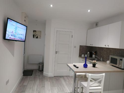 a kitchen with a table and a tv on a wall at Oceanik in Dublin