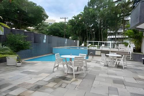 a patio with tables and chairs next to a pool at bwelcome - aconchego pé na areia mod 2 in Bertioga