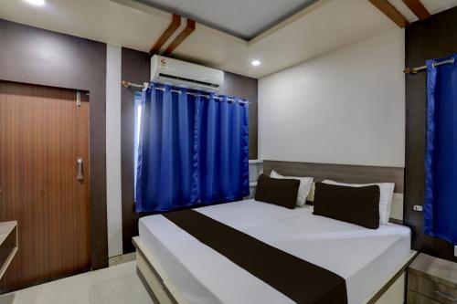 Un pequeño dormitorio con una cama con cortinas azules en OYO Anusuya Hotel en Bhubaneshwar
