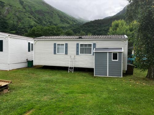 une maison blanche avec une échelle dans une cour dans l'établissement Mobil-home Gère-Bélesten, à Gère-Belesten