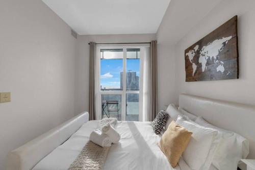 a bedroom with a large white bed with a window at Rare 1BR - Rooftop Pool, Next to MTCC & CN Tower in Toronto