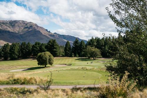 a view of a golf course with mountains in the background at Loi Suites Chapelco Hotel in San Martín de los Andes